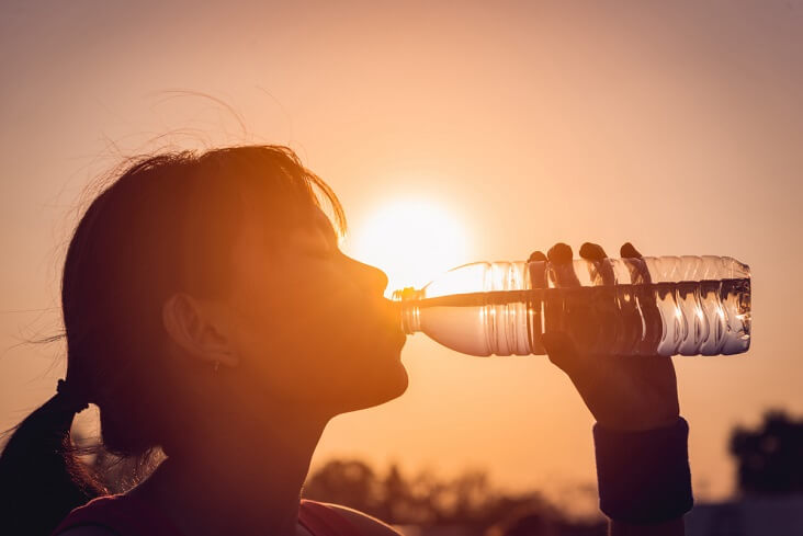 Female drinking a bottle of water silhouette.