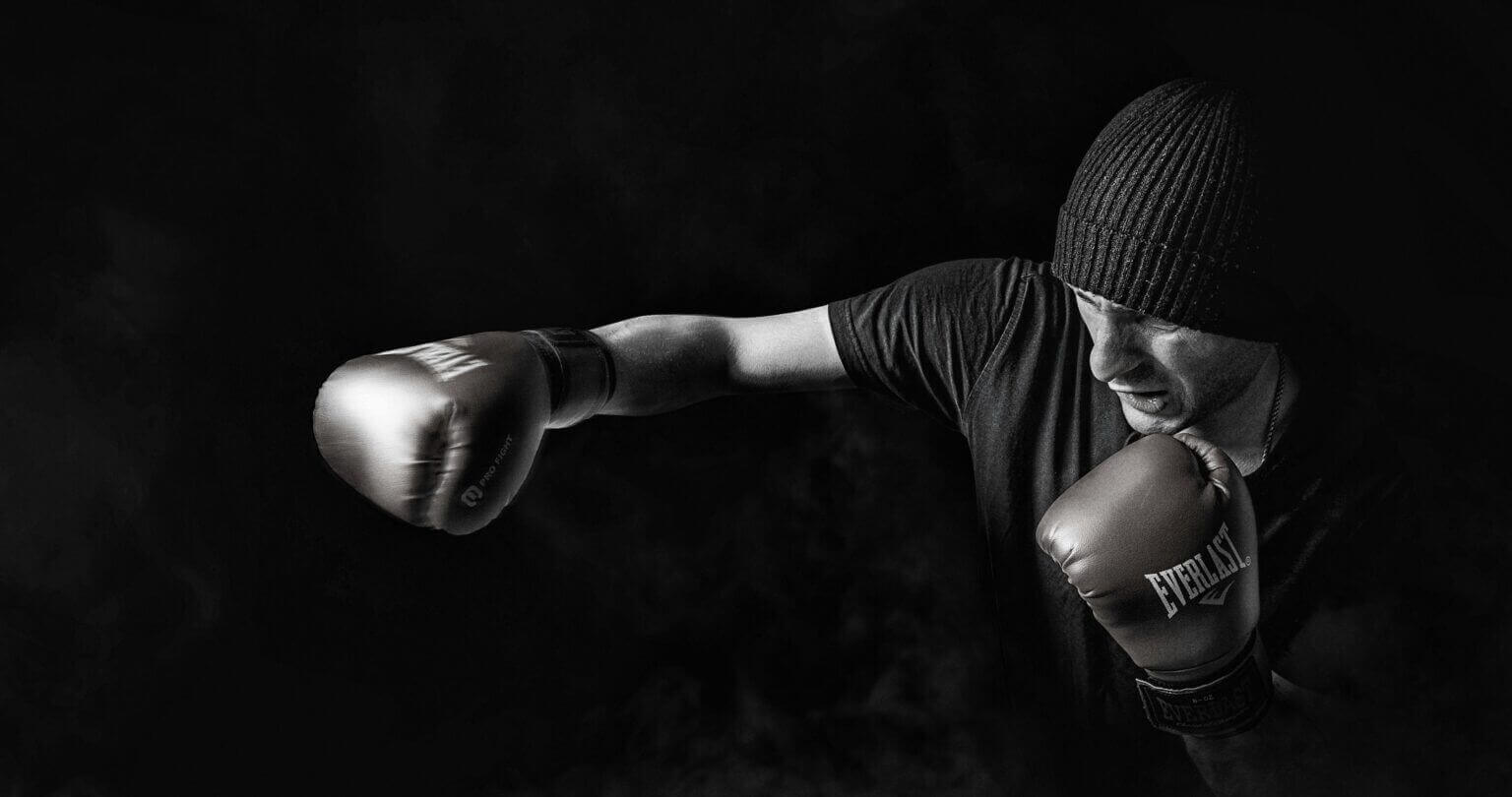 Jake Paul in a boxing ring, wearing gloves and athletic gear, mid-pose with determination in his stance and focus in his eyes.