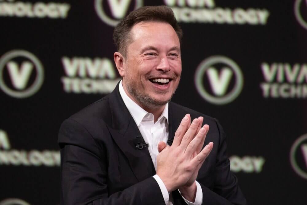 Elon Musk, the billionaire entrepreneur and CEO of Tesla and SpaceX, speaking at an event with a thoughtful expression, reflecting his enigmatic and unconventional persona.