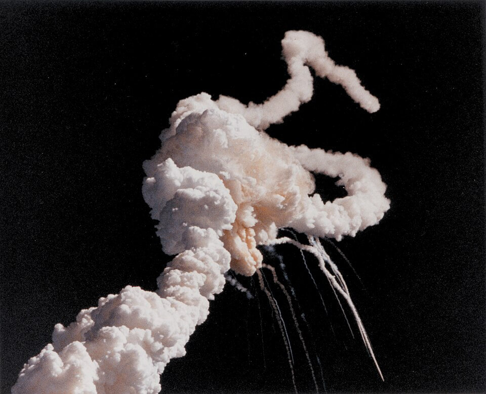 Challenger's solid rocket boosters fly uncontrollably after the breakup of the external tank separated them from the shuttle stack. The remains of the orbiter and tank leave thin white trails as they fall toward the Atlantic Ocean. 