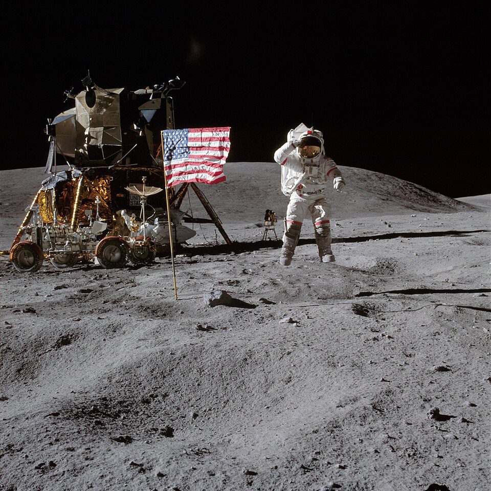 Astronaut John Young saluting the US flag while jumping on the Moon during Apollo 16 with lunar module Orion and rover