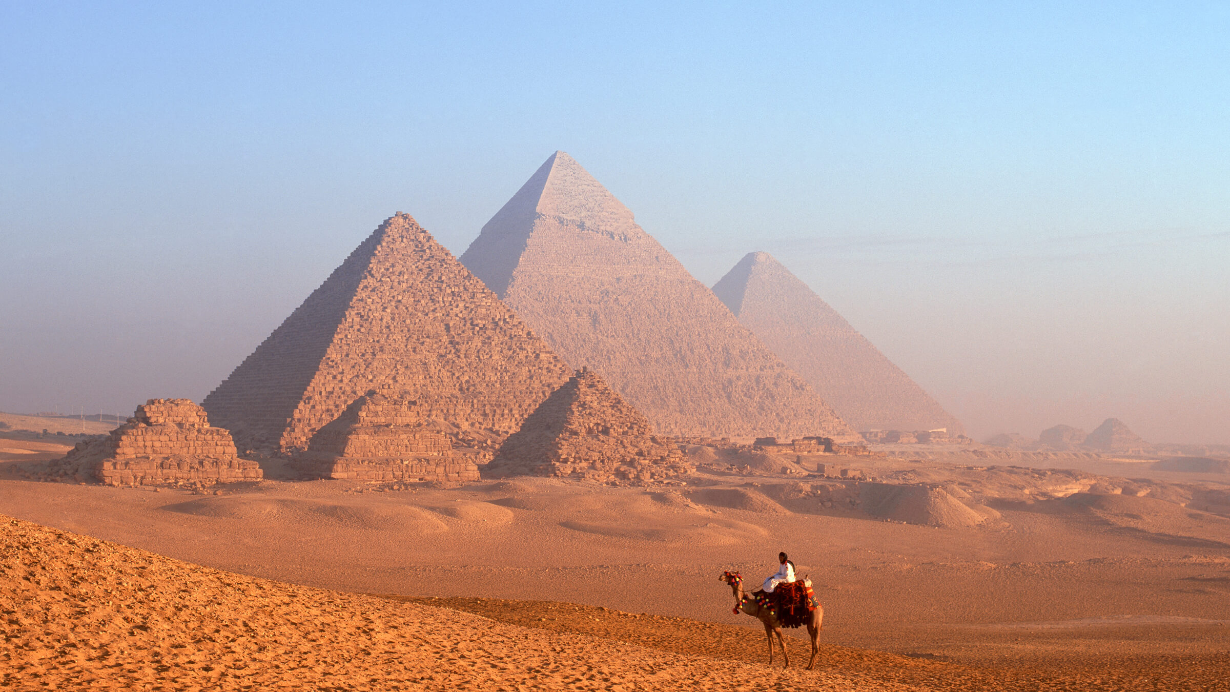 Bedouin man riding a camel near the Giza Pyramids in Egypt.