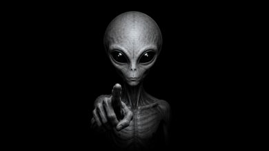 Grey alien pointing against a plain black background