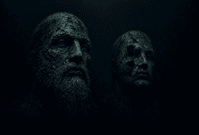 Ancient human-like stone faces resting underwater, covered in marine growth and sediment.